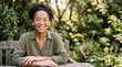 © Raphael - A Woman with Vitiligo Smiling in a Garden: A beautiful young woman with vitiligo smiles warmly while sitting at a wooden table in a sun-dappled garden.