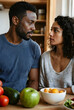 © Pixel-Shot - Young african american couple looking at each other in a kitchen with fresh fruits and vegetables on the counter