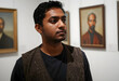 © Pixel-Shot - Young indian man in a patterned vest looking at art in a gallery, cultural exploration and museum visit, the mans thoughtful expression suggests contemplation and engagement with the artwork