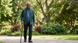 © OlgaNeuroArt - Senior African American man walking with a cane in a park. Smiling elderly male enjoying an outdoor stroll on a sunny day. Active retirement and mobility support concept