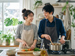 © Anoconone - 雪景色が広がる窓辺のキッチンで楽しく料理を作る笑顔の女性