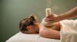 © Vatrick - Close up shot of a therapist pressing a steaming herbal compress ball onto a woman back in spa.