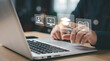 © Khan - Hands interacting with a laptop displaying e-learning concept icons including a graduation cap, open book, video play button, and user profile on a blurred background featuring online education