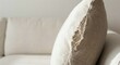 © khmelev - Close-up view of a torn beige linen pillow with frayed seam sitting on a comfortable modern sofa
