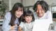 © pattozher - Family Connection with Technology: A heartwarming scene of a young family, parents and their daughter, gathered around a laptop, sharing a moment of learning and connection in their cozy home.