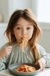 © Andrii Zastrozhnov - Young girl eating spaghetti at home for food blog and recipe background with natural light candid family mealtime portrait