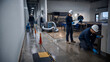 © AiHRG Design - Professional restoration technicians inspect and dry a flooded commercial interior using industrial equipment, safety gear, and moisture testing tools.