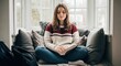 © Rasyid - A serene young woman wearing a warm knitted sweater sits comfortably on a plush window seat while peacefully reading a thick book during a quiet afternoon in her cozy and bright suburban home