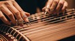 © Angavlan - Hands playing traditional musical instrument with intricate rings and long nails, showcasing unique craftsmanship and artistry.