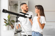 © Pixel-Shot - Young couple with telescope at home