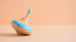 © LarisaM - Minimal close-up of a colorful wooden spinning top on a soft pastel background, representing classic childhood toys, balance, motion, learning, and timeless play.