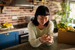 © Davor - Woman using smartphone in kitchen with fresh grocery delivery