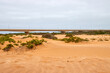 © Jane Be. The Picture - Eine flache Sandlandschaft mit niedrigen Pflanzen und einer Brücke ist in der Wüste bei Swakopmund in der Region Erongo, Namibia, zu sehen.