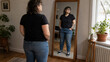 © Infinity in the lens - Curvy woman looking at her reflection in a full-length mirror at home. Body image, self-acceptance, confidence, body positivity, personal style and everyday lifestyle concept.