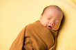 © leungchopan - Sleeping newborn baby wrapped in brown cloth in taiwan