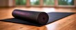 © Rodriguez - Rolled black exercise mat on a wooden floor