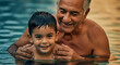 © SYATRI RAWU - Happy grandfather teaching his young grandson how to swim in a blue outdoor pool during a sunny summer vacation, multi-generational bonding and fun.