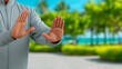 © nuanjan - Person standing outdoors showing stop hand gesture against tropical blurred background for communication and boundary concept photography