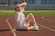 © ksenija1803z - Tired young girl sitting on running track and shielding her eyes from sun during sport training outdoors