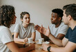 © Pixel-Shot - Diverse group of young adults having a serious discussion over coffee at a cafe table, communication and teamwork, this scene concepts of teamwork collaboration and social interaction among