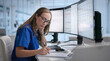 © Andrey Popov - Young Female Doctor Focused On Updating Patient Records
