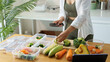 © matinee - Woman cutting fresh broccoli while preparing healthy vegetable meals in reusable food containers at home. Nutrition and healthy lifestyle concept.
