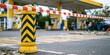 © Anastasiya - Close-up of a yellow bollard with red and white barrier tape blocking a gas station entrance.