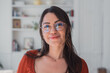 © Daniel - Woman with dark hair and gold-rimmed eyeglasses smiling softly, reflecting a confident and intelligent persona in an indoor setting, representing business, learning, and everyday life