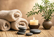 © Visi Hue - Spa setting with rolled fluffy towels, smooth hot stones, and a lit candle creating a relaxing atmosphere.
