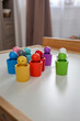 © Volha - Colorful Montessori color sorting toy with wooden figures arranged on a children's table in a modern playroom.