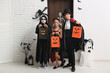 © Pixel-Shot - Kids dressed for Halloween with gift bags at door in hall