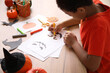 © Pixel-Shot - Teenage African-American boy drawing Halloween card at table, closeup