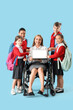 © Pixel-Shot - Mature teacher in wheelchair with little pupils pointing at laptop on blue background