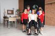 © Pixel-Shot - Mature Geography teacher in wheelchair hugging little pupils at school