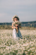 © svetograph - Joyful child holding Leucanthemum vulgare bouquet while standing in sunny meadow during warm summer day