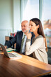 © gzorgz - Two mid-aged business people working together on a laptop in a modern office
