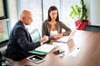 © gzorgz - Two mid-aged business people working together on a laptop in a modern office