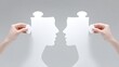 © justjupiter - Two hands hold profile-shaped puzzle pieces facing each other, symbolizing connection, communication, or understanding.