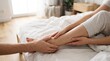 © Armando Loho - Man massaging woman legs while sitting on bed in bright bedroom