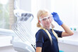 © Alla - A little blonde girl in blue gloves put a transparent screen over her eyes and face. Dental office. Profession - dentist. Copy space
