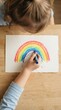 © SimpleDesignStudio - Young toddler girl drawing a colorful rainbow with pastel crayons on paper at a wooden table