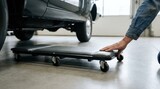 Mechanic preparing a wheeled creeper to slide underneath a car in an auto repair garage