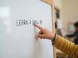 © SimpleDesignStudio - Toddler Child Pointing at Whiteboard with Learn and Grow Text in Classroom Setting