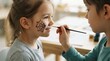 © SimpleDesignStudio - Little caucasian girl getting face paint spider web by friend in classroom