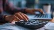 © Athazio - Person using calculator and laptop for finances