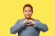 © Pixel-Shot - Cute little African-American boy showing heart gesture on yellow background. Valentines day celebration