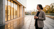 © Elizabeth - Confident businesswoman holding coffee cup standing on a modern office building terrace at sunset