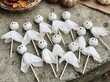 © MDASHIR - Group of handmade ghost lollipops wrapped in white tissue paper with black ink faces on stone background.