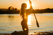 © Darius - Woman kneeling on a paddleboard on a lake during a golden sunset in the summer