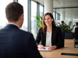 © SINNBILD Design - Dunkelhaarige Frau in eineem hellen Büro beim Personalgespräch. Eine Bewerberin zeigt Selbstbewusstsein in der Körpersprache und hält freundlichen Blickkontakt